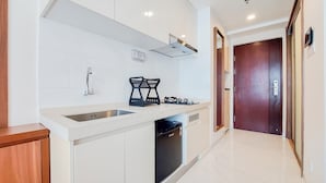 A modern kitchen with white cabinets, a stainless steel sink, a built-in dishwasher, and a black gas stove.