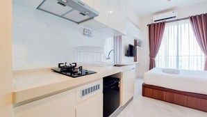 Una camera d'albergo compatta con angolo cottura, un letto e una televisione.