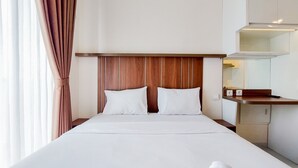 Una camera d'albergo con una testiera in legno, un letto con lenzuola bianche, un comodino e uno specchio sopra.