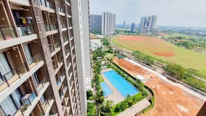 A high-rise building with multiple balconies, a swimming pool, and a sports field in the background. - Fancy And Nice Studio At 20Th Floor Sky House Bsd Apartment (Pagedangan)