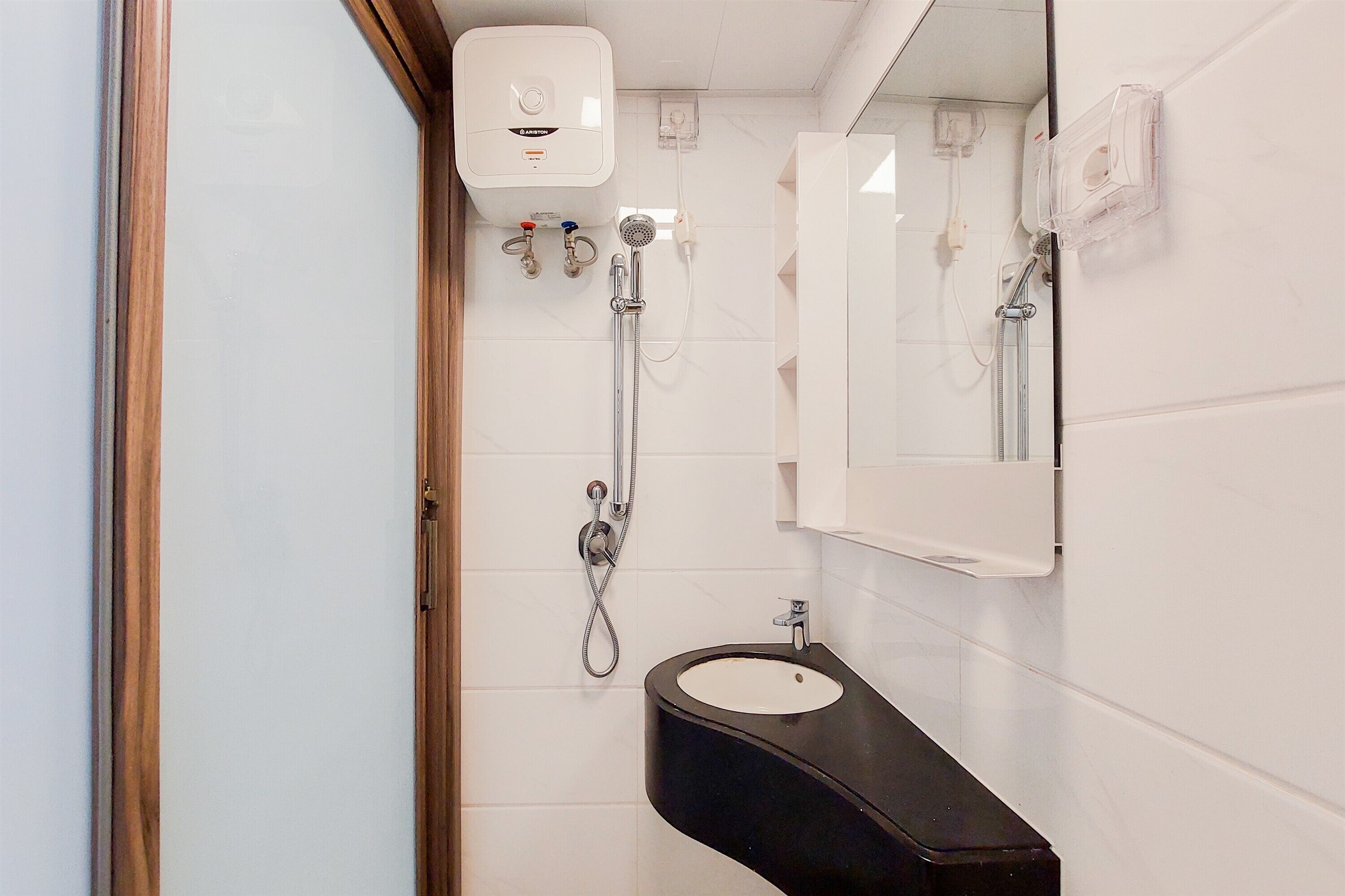 Een badkamer met een zwart wastafel, een spiegel, een douche met een handdouche en een wandradiator.