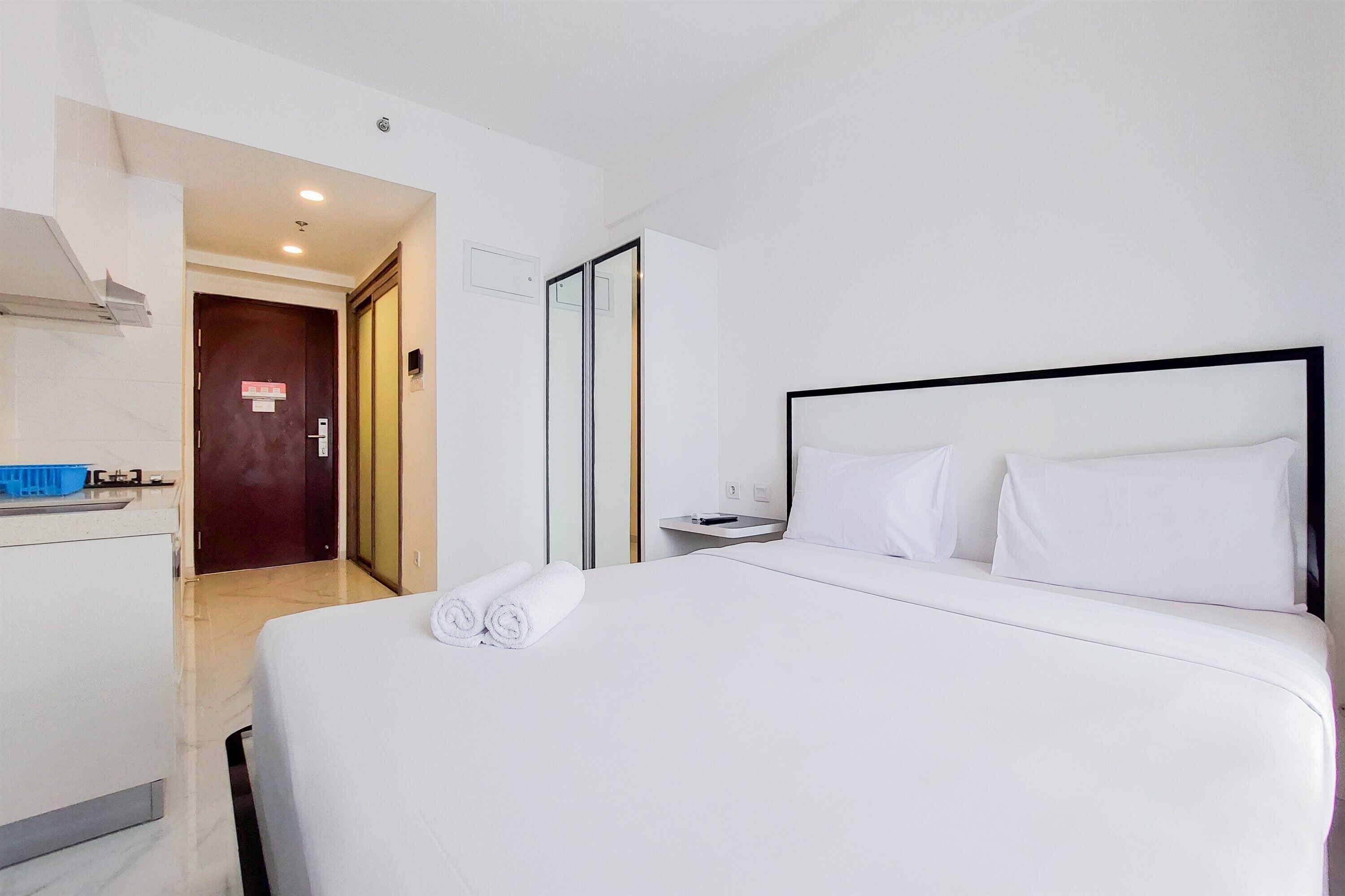 A hotel room with a bed, a desk, and a bathroom door.