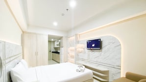 Une chambre d’hôtel moderne dotée d’un grand lit, d’un téléviseur fixé au mur et d’un coin salon séparé.