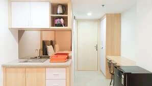 A compact kitchen with a sink, countertop, and cabinets. There is a refrigerator and a microwave on the right. - Cozy Studio Room At De Prima Apartment (Medan)