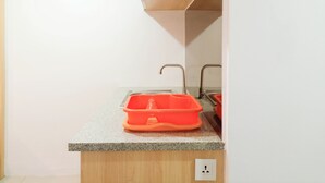 A kitchen with a granite countertop, a sink, and a wooden cabinet. - Cozy Studio Room At De Prima Apartment (Medan)