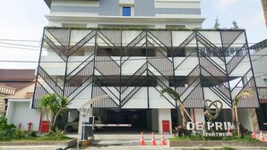 A multi-story building with a modern design, featuring a central staircase and a gated entrance. - Cozy Studio Room At De Prima Apartment (Medan)