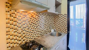 Una cocina con protector contra salpicaduras de mosaico, un lavamanos de acero inoxidable y una estufa a gas.