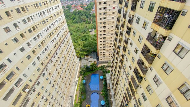Un edificio de gran altura con un patio central que tiene una piscina, rodeado de balcones y vegetación.