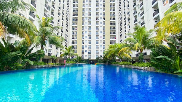 A swimming pool surrounded by tall residential buildings and palm trees. - Fancy And Nice 2Br At Cinere Resort Apartment (Depok)
