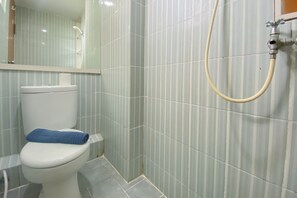A bathroom with a toilet, a shower, and a mirror. - Fancy And Nice 2Br At Cinere Resort Apartment (Depok)