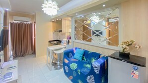 A modern kitchen with a bar area, a blue sofa with leaf patterns, and a decorative mirror. - Fancy And Nice 2Br At Cinere Resort Apartment (Depok)