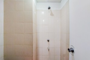 Una ducha con cabezal de ducha instalado en el techo y grifo en la pared.