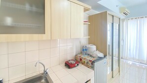 A modern kitchen with a stainless steel sink, a red electric kettle, and a refrigerator. - Homey And Cozy Stay Studio Margonda Residence 3 Apartment (Depok)