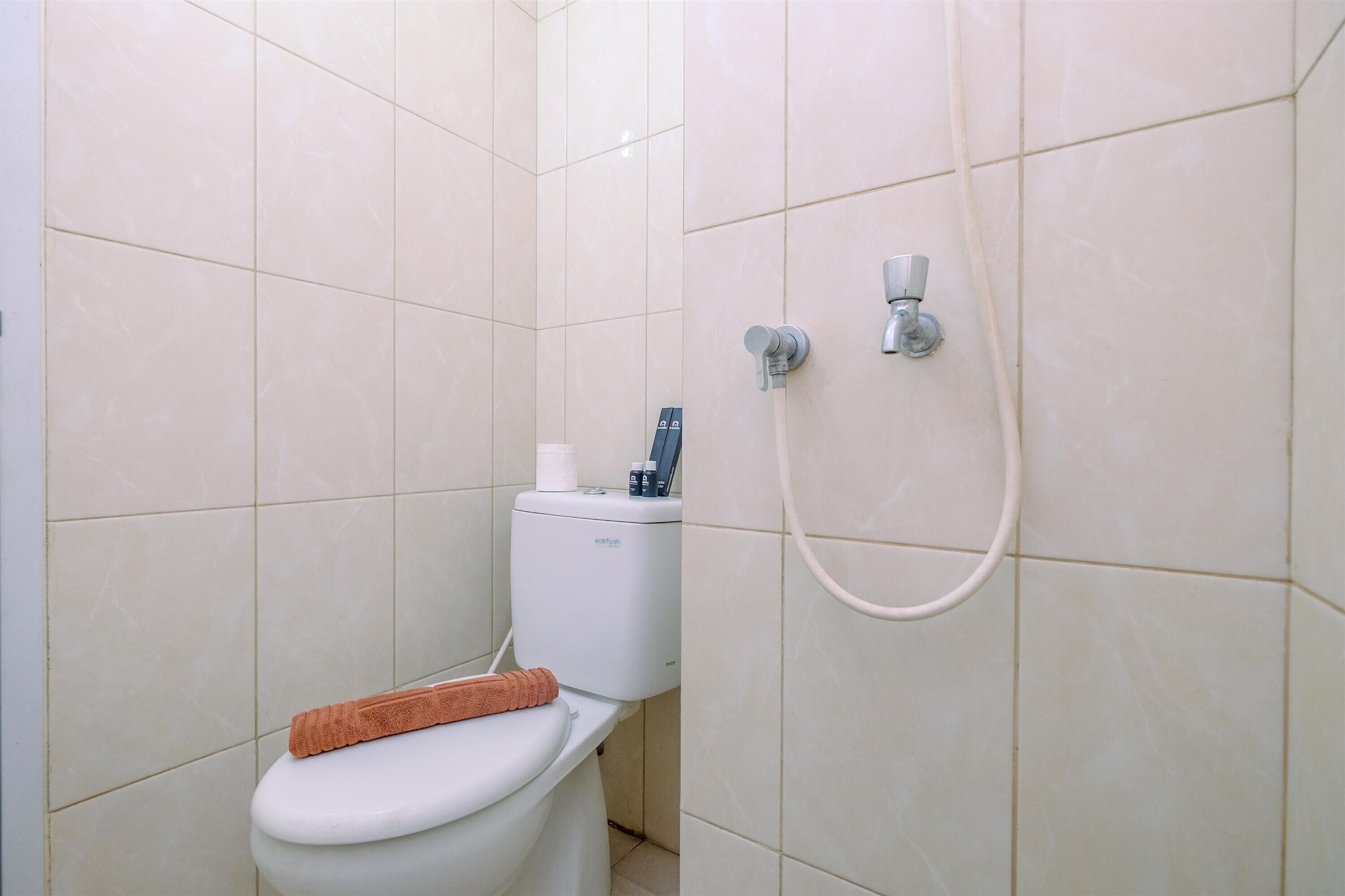 A bathroom with a toilet, a shower, and a towel on the seat.