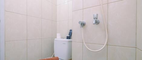 A bathroom with a toilet, a shower, and a towel on the seat.