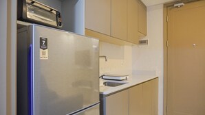 Una cocina compacta con un refrigerador de acero inoxidable, un microondas y un horno empotrado.