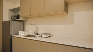 Una cocina con refrigerador, lavamanos, tostadora y encimera blanca.