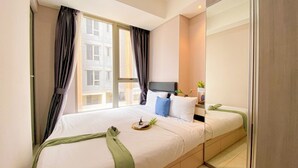 Ett hotellrum med en stor säng, en platt-TV, ett litet bord med en växt och utsikt över byggnader genom fönstret.