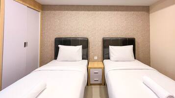 A twin room with two single beds, a wooden nightstand, and a white wardrobe.