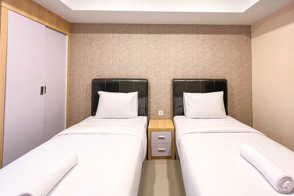 Two single beds with matching headboards and white bedding, each with a nightstand and a towel.