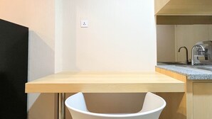 A compact kitchen with a wooden countertop, a sink, and a white chair.