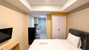 A hotel room with a bed, a TV on a stand, a desk with a chair, and a wardrobe.