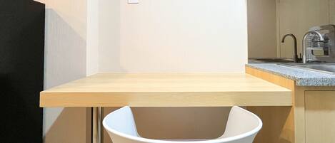 A compact kitchen with a wooden countertop, a sink, and a white chair.