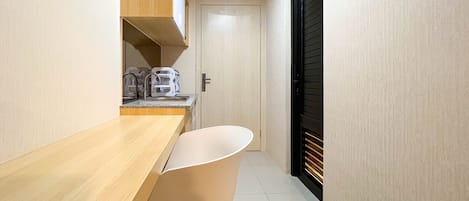 A narrow hallway with a wooden counter and a white chair. A door with a black shutter is visible in the background.