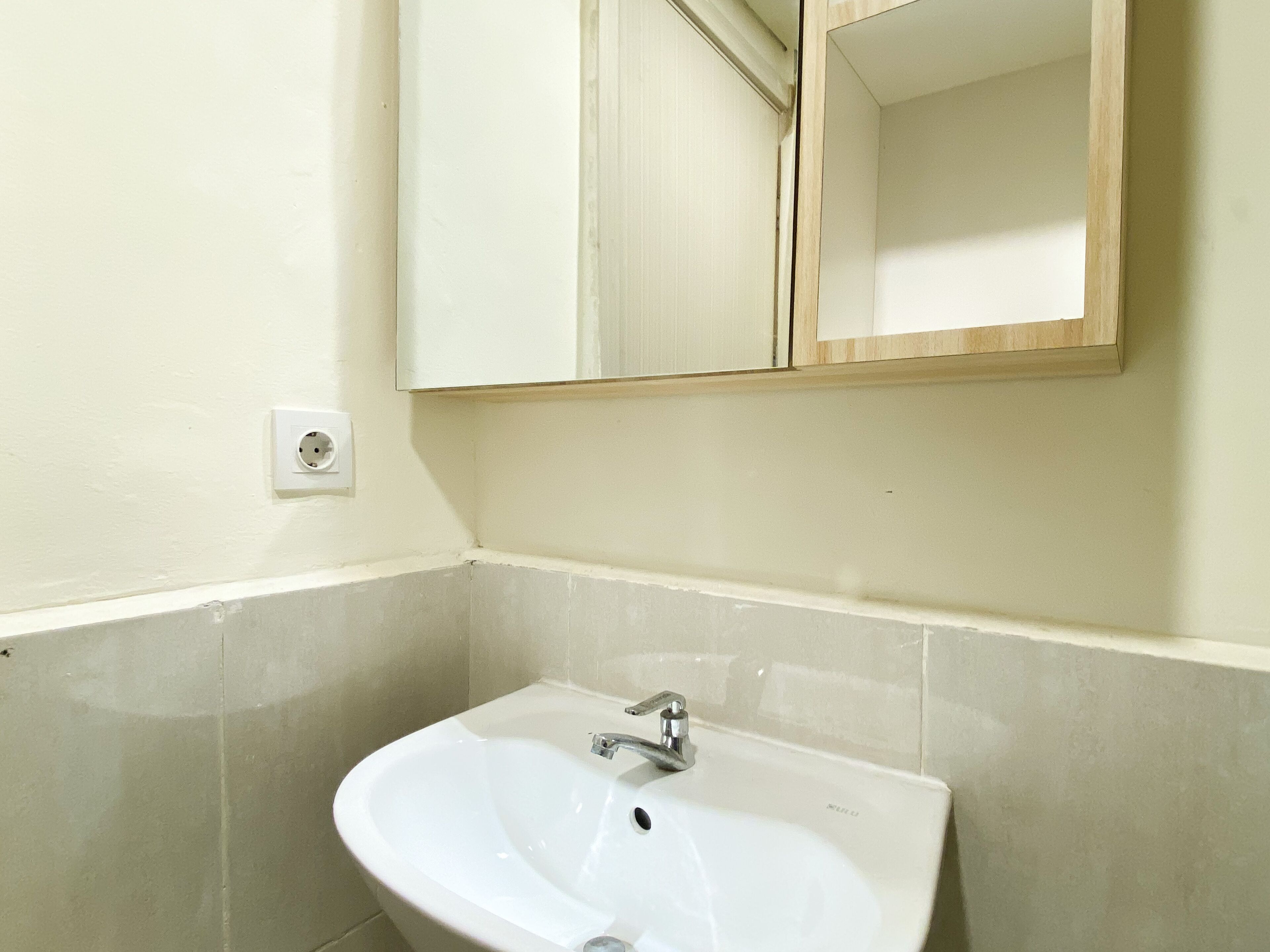 A bathroom with a white sink, a mirror, and a light switch on the wall.