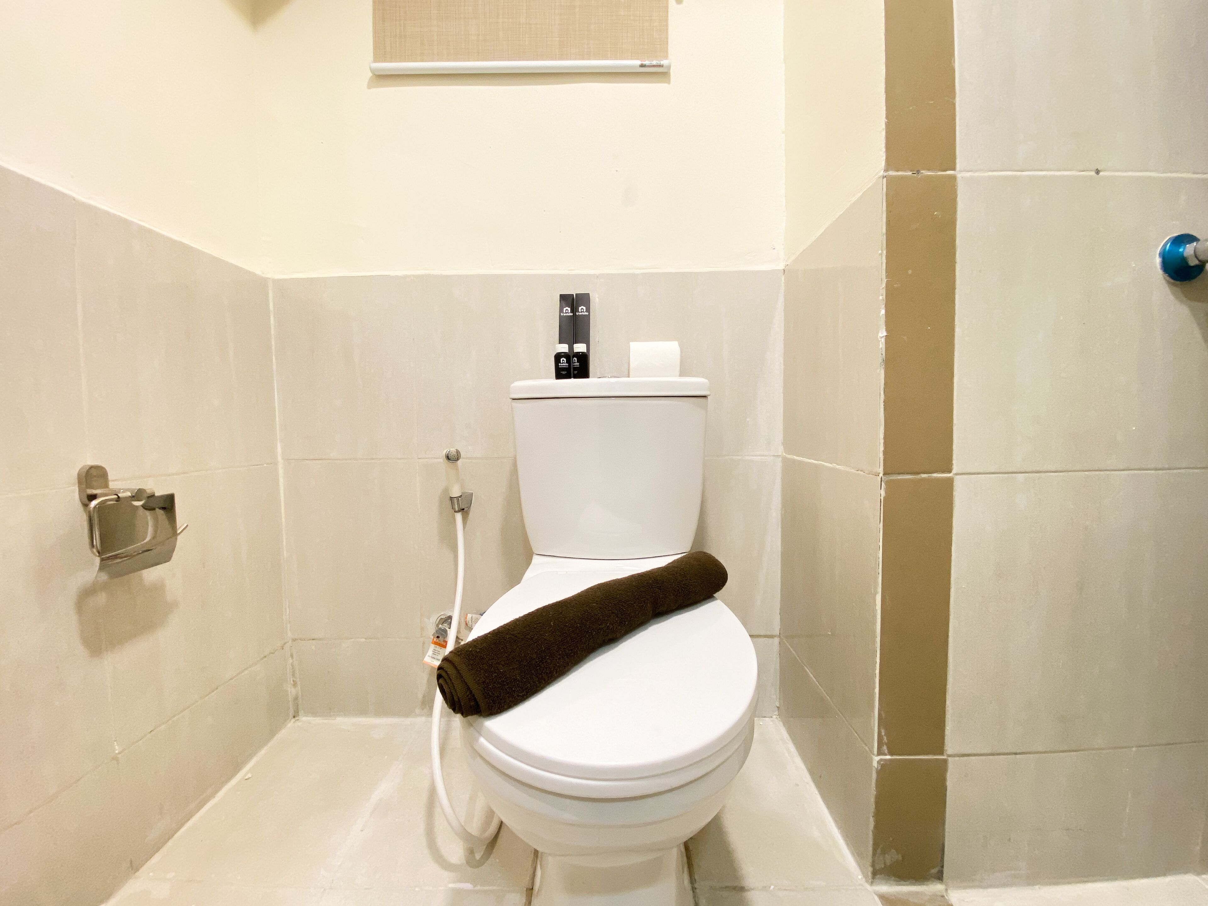 A bathroom with a toilet, a towel rack, and a shower area.