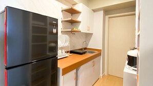 A compact kitchen with a black refrigerator, white cabinets, a wooden countertop, and a built-in sink. - Comfort Stay And Simply 2Br At Meikarta Apartment (Cikarang)