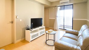 A living room with a sofa, TV, and a small table. - Comfort Stay And Simply 2Br At Meikarta Apartment (Cikarang)