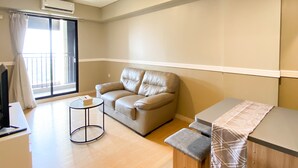A modern living room with a leather sofa, a small round table, and a bench. - Comfort Stay And Simply 2Br At Meikarta Apartment (Cikarang)