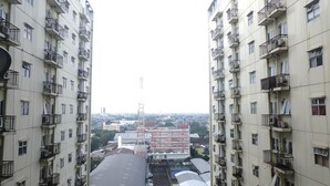 A high-rise building with multiple balconies and a large parking area in the foreground. - Good Deal 2Br At 16Th Floor Suites @Metro Apartment (Bandung)
