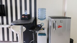 A kitchenette with a water dispenser, a refrigerator, and a small table with a sink. - Good Deal 2Br At 16Th Floor Suites @Metro Apartment (Bandung)
