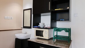 A bathroom with a white sink, a microwave, a green basket, and a mirror. - Simply 2Br (No Kitchen) At Apartment Marbella Suites Dago Pakar Bandung (Bandung)
