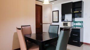 A dining area with a black table and chairs, a microwave, and a cabinet with shelves. - Simply 2Br (No Kitchen) At Apartment Marbella Suites Dago Pakar Bandung (Bandung)