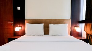 A hotel room with a large bed, two bedside tables with lamps, and a wooden headboard. - Simply 2Br (No Kitchen) At Apartment Marbella Suites Dago Pakar Bandung (Bandung)