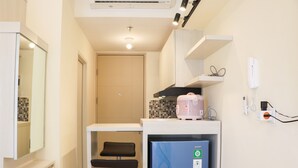 A compact kitchen with a refrigerator, a microwave, and a small countertop. - Nice And Homey Studio Tokyo Riverside Pik 2 Apartment (Teluknaga)