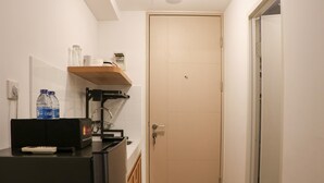 A small bathroom with a toilet, sink, and shelf with toiletries. - Relaxing Studio Apartment At Tokyo Riverside Pik 2 (Teluknaga)