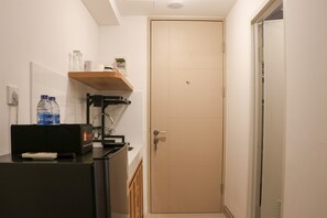 A compact bathroom with a sink, mirror, and shelf, offering a convenient space for personal care.