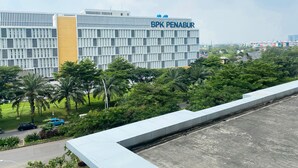 A modern building with the sign "BPK PENABUR" on top, surrounded by lush greenery and a clear sky. - Restful And Simply Studio Springlake Summarecon Bekasi Apartment (Bekasi)