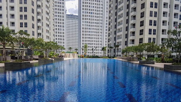 Une piscine entourée de grands immeubles, sous un ciel dégagé.
