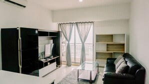 Un salon moderne doté d’un téléviseur à écran plat, d’un meuble de rangement noir pour appareils multimédias, d’une table basse en verre, d’un canapé en cuir noir et d’une grande fenêtre ornée de rideaux légers.
