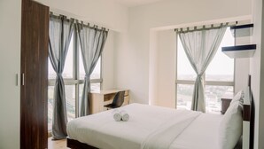 Une chambre d’hôtel avec un grand lit, un bureau et une vue sur la ville par les fenêtres.