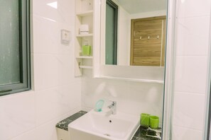 A bathroom with a white sink, green toiletries, and a wooden cabinet. - Comfort And Modern Look 3Br Sky House Bsd Apartment (Pagedangan)