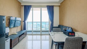 Una moderna camera d'albergo con balcone, televisione a schermo piatto, tavolo da pranzo con piano in marmo e minibar.