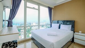 Una camera d'hotel moderna con un ampio letto, una scrivania e vista sulla città attraverso grandi finestre.