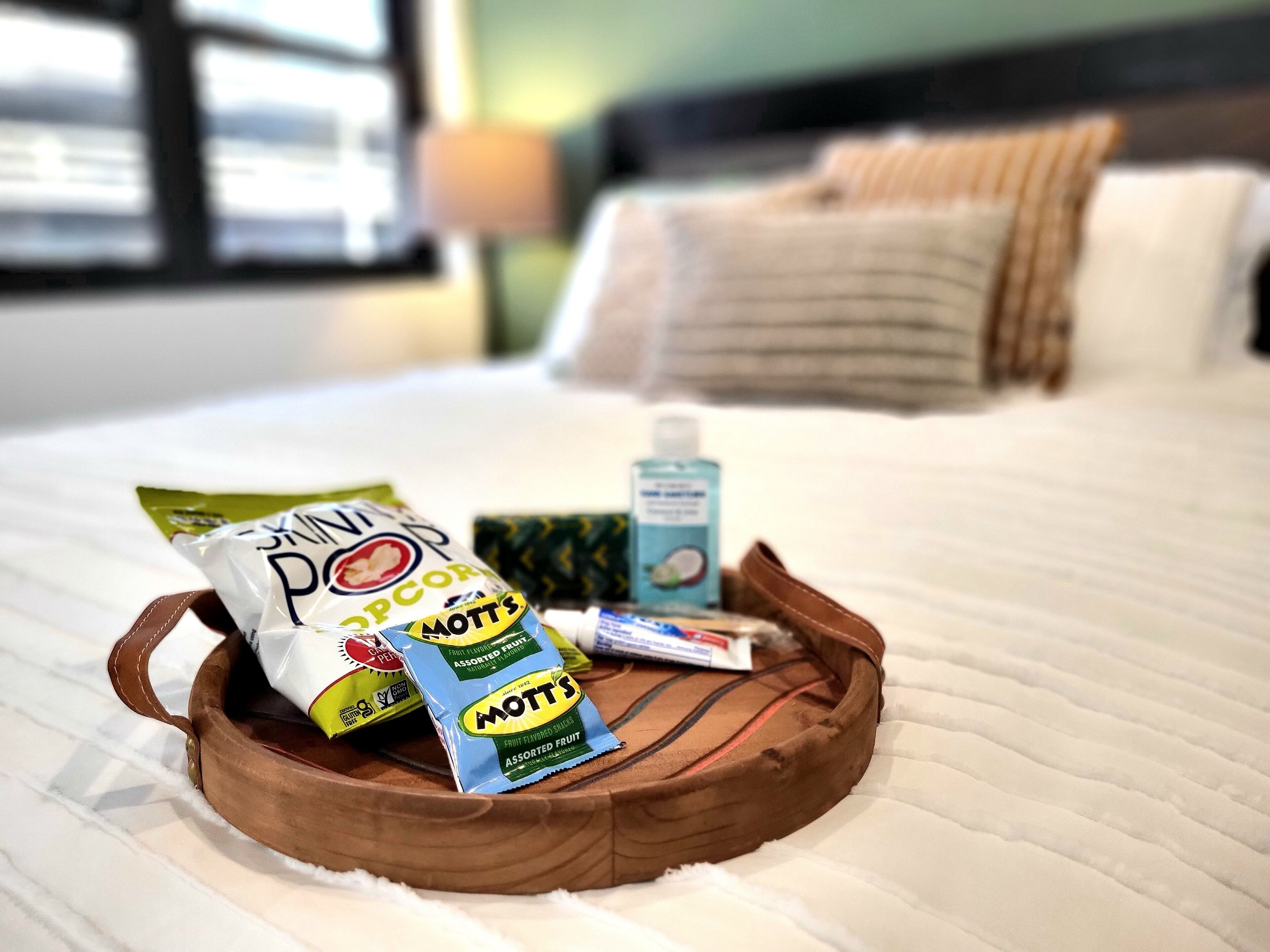 Un lit avec un plateau en bois sur lequel se trouvent des collations et une petite bouteille.