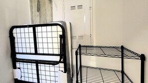 Una habitación con una puerta blanca, un perchero metálico y una estantería de metal.